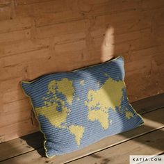 a blue and yellow pillow sitting on top of a wooden floor next to a wall