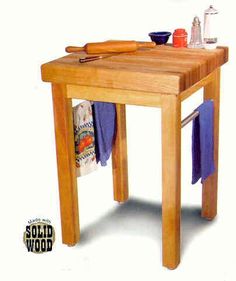 a small wooden table with a cutting board and knifes on the top, next to a towel rack