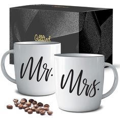 two white coffee mugs with mr and mrs written on them next to a box