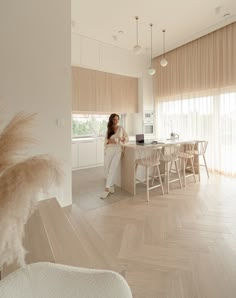 a woman standing in the middle of a kitchen next to a dining room table and chairs