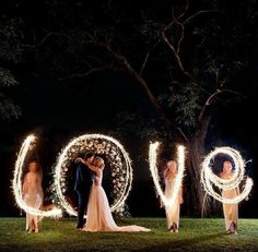 a bride and groom standing in front of the word love with sparklers around them