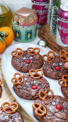 cookies decorated with reindeer noses and eyes are on a white plate next to oranges