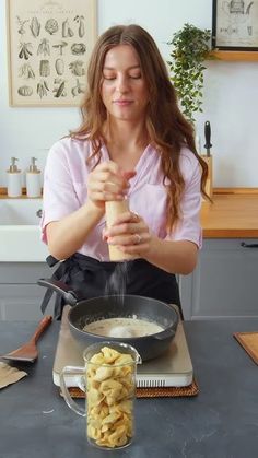 a woman is cooking food in a pot on the kitchen counter with utensils