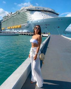 a woman standing next to the ocean with a cruise ship in the background