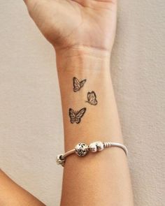 a woman's wrist with three butterflies tattooed on the side of her left arm