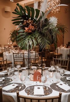 a table set up with place settings and flowers in vases on the centerpiece