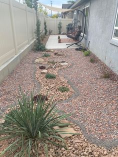 a graveled back yard with rocks and plants