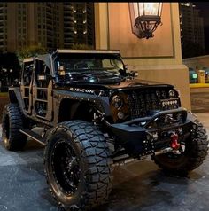 a black jeep parked in front of a tall building with lights on it's sides