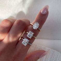 a woman's hand with three rings on her fingers and two diamonds in the middle