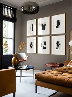 a living room filled with furniture and pictures on the wall next to a window in front of it