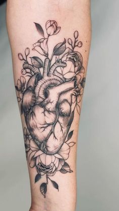 a black and white heart tattoo with flowers on the side of the calf's leg