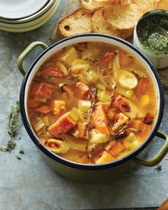 a pot filled with soup next to some bread