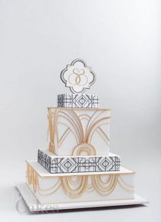 a three tiered cake decorated with gold and black designs