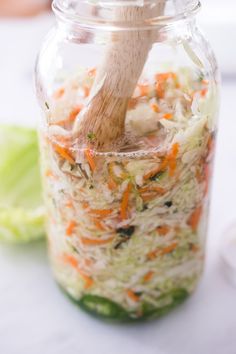 a wooden spoon in a jar filled with shredded vegetables