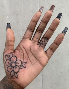 a person's hand with tattoos on it and flowers on the middle finger,