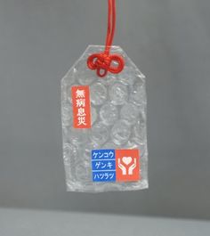 a clear plastic bag with red string hanging from it's side on a gray surface