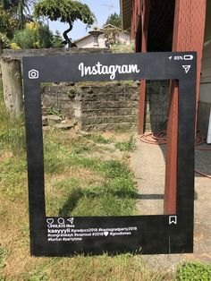 an instagram sign on the side of a road in front of a building with grass growing around it