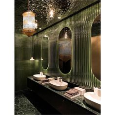 a bathroom with green walls and two sinks in front of the mirror that is hanging from the ceiling