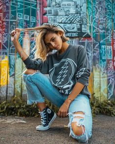 a woman sitting on the ground in front of graffiti