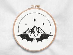 a cross stitch pattern with mountains and bats in the middle, on a white background