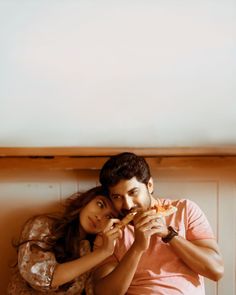 a man and woman are sitting together eating pizza