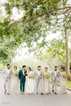 a group of people standing next to each other in front of some trees and grass