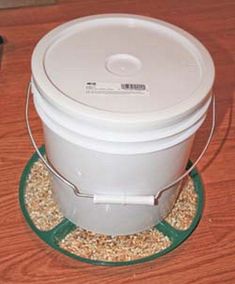 a white bucket sitting on top of a wooden table next to a metal container filled with oats