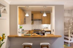 a kitchen with two stools next to a counter and stairs in the back ground