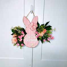 a pink bunny door hanger with flowers and greenery