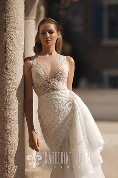 a woman in a wedding dress leaning against a pillar