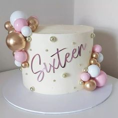 a white cake with pink, gold and white balloons on it that says glitter