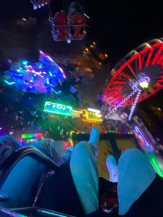 the view from inside a carnival ride at night time with ferris wheel and neon lights