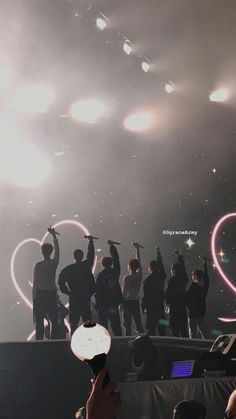 a group of people standing on top of a stage with fireworks in the sky behind them