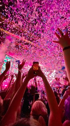 a group of people in a room with confetti on the ceiling and one person holding up a cell phone