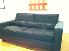 a black couch sitting on top of a hard wood floor