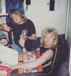 two people sitting on a couch with books and drinks in front of them, one holding a beer bottle