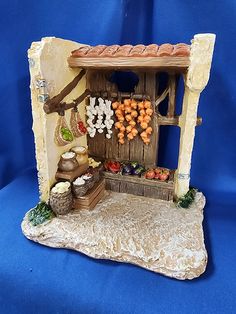 a miniature model of a small store with fruits and vegetables on the shelf in front of it