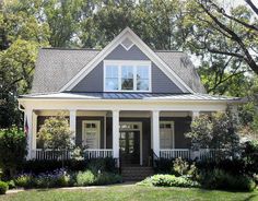 a house that is in the grass with trees and bushes on both sides of it