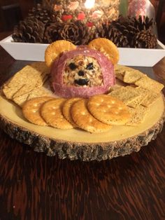 a plate with crackers, cheese and meat in it on a table next to pine cones