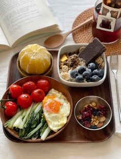 a tray filled with different types of food on top of a table next to an open book