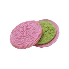 two cookies with green and pink frosting on them, one has a cookie in the middle