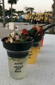 two plastic cups filled with food sitting on top of a table