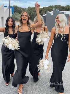 three women in black dresses are walking together and one woman is holding her hand up