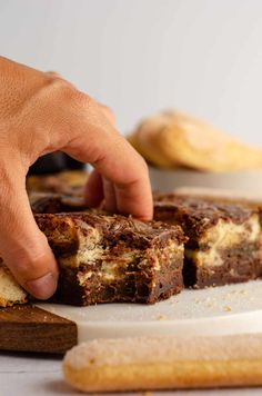 a hand picking up some brownies from a plate