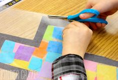 a child is cutting paper with scissors on a table