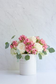 a white vase filled with pink and white flowers