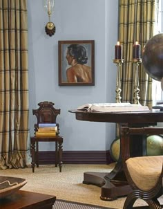 a living room filled with furniture and a painting hanging on the wall next to a window