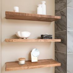 two wooden shelves in a bathroom next to a mirror and soap dispenser