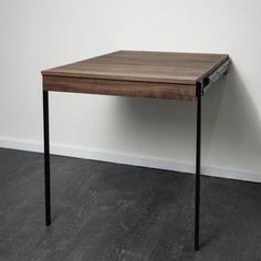 a small wooden table sitting on top of a hard wood floor next to a white wall