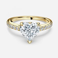 a yellow gold engagement ring with a heart shaped diamond in the center and side stones